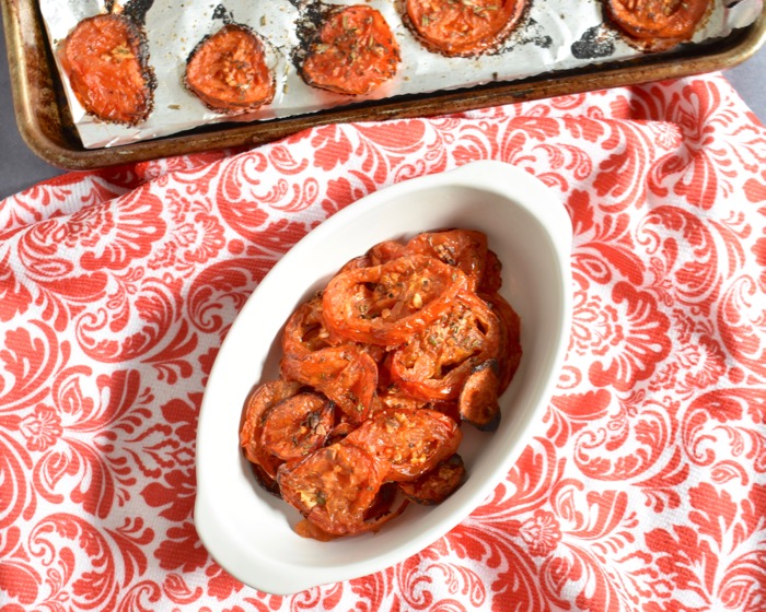 oven roasted tomatoes in white ramekin on red and white paisley tablecloth