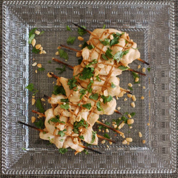 Thai peanut chicken satay marries the heat of sriracha with the coolness of coconut milk and cilantro. Served with an easy peanut sauce as an appetizer or main dish, this recipe is sure to be a crowd pleaser. Get the gluten-free recipe at JessicaLevinson.com | #ChickenSatayRecipe #EasyPeanutSauce #ChickenAppetizer Thai Peanut Chicken Satay Overhead on Plate