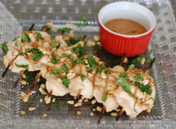 Thai peanut chicken satay marries the heat of sriracha with the coolness of coconut milk and cilantro. Served with an easy peanut sauce as an appetizer or main dish, this recipe is sure to be a crowd pleaser. Get the gluten-free recipe at JessicaLevinson.com | #ChickenSatayRecipe #EasyPeanutSauce #ChickenAppetizer Thai Peanut Chicken Satay on Plate with Peanut Sauce