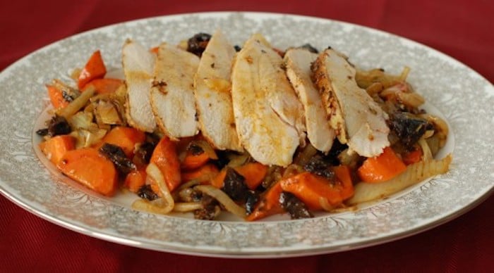 Juicy, savory, and flavorful roasted chicken with fennel, carrots, onions, and dried plums is easy enough for a weeknight meal and elegant enough for company. Also a great recipe for leftovers - if there are any! Get the gluten-free and dairy-free recipe via JessicaLevinson.com #RoastedChickenRecipe #EasyChickenRecipe Roasted Chicken with Fennel Sliced on Serving Platter