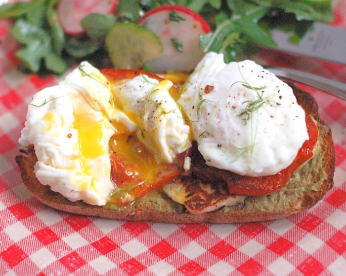 Smoky halloumi, fragrant roasted tomatoes, creamy avocado, and poached eggs top whole grain sourdough bread in this Mediterranean style egg and cheese sandwich. Get the recipe @ JessicaLevinson.com | #eggs #eggandcheese #meditteraneandiet #breakfast #brunch #breakfastfordinner #vegetarian Mediterranean style egg and cheese sandwich with roasted tomatoes, poached eggs, and halloumi cheese