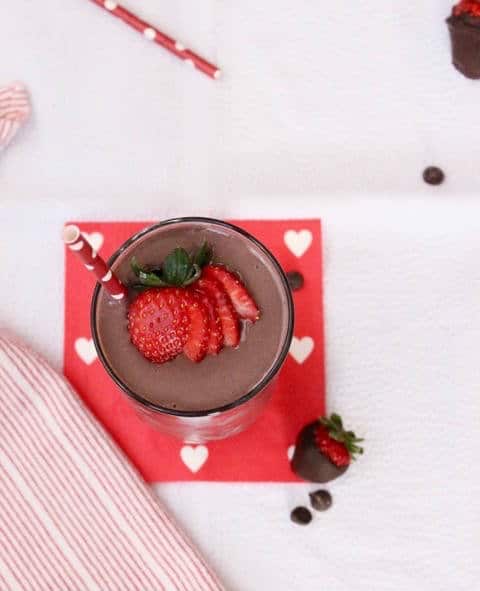 Dark chocolate, creamy greek yogurt, and sweet strawberries are the perfect combination in this frosty, high protein and heart-healthy Valentine's Day Dark Chocolate Strawberry Smoothie! Get the gluten-free and vegetarian recipe via JessicaLevinson.com | #strawberrysmoothierecipe #chocolatesmoothie #proteinsmoothie Dark Chocolate Strawberry Smoothie in Cup Overhead