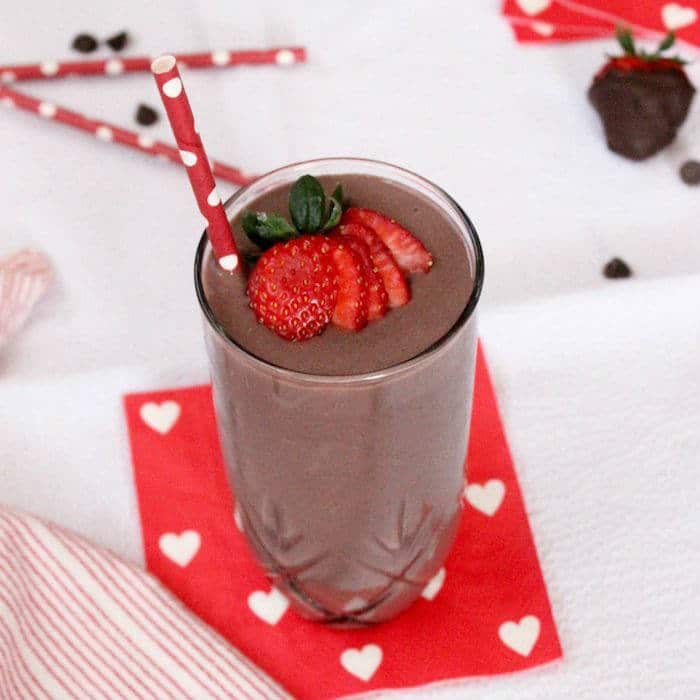 Dark chocolate, creamy greek yogurt, and sweet strawberries are the perfect combination in this frosty, high protein and heart-healthy Valentine's Day Dark Chocolate Strawberry Smoothie! Get the gluten-free and vegetarian recipe via JessicaLevinson.com | #strawberrysmoothierecipe #chocolatesmoothie #proteinsmoothie Dark Chocolate Strawberry Smoothie in Cup