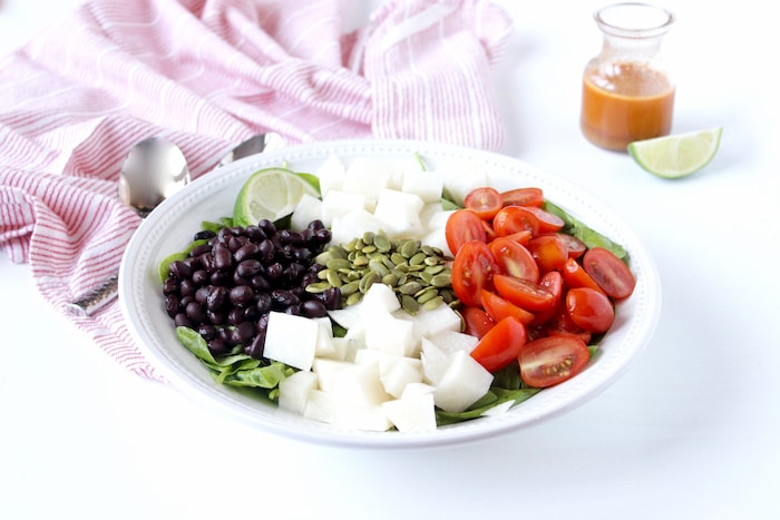 Crisp spinach, crunchy jicama, juicy tomatoes and tender black beans are tossed with a smoky lime vinaigrette in this quick and easy side salad that's the perfect accompaniment to your favorite Mexican-inspired dinner. Vegan, dairy-free, and gluten-free. Get the Spinach Salad with Jicama recipe via JessicaLevinson.com | #SpinachSaladRecipe #JicamaSalad spinach salad with jicama ingredients
