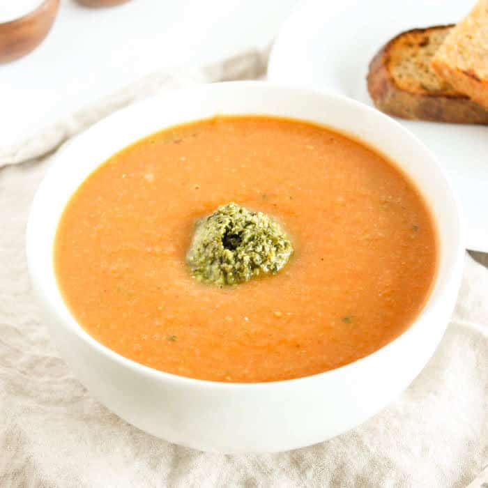 Warm up this fall and winter with a bowl of tomato white bean soup topped off with a dollop of kale pesto. Gluten free, vegetarian, and vegan-friendly. Recipe via JessicaLevison.com #TomatoSoupRecipe #VegetarianSoup Tomato White Bean Soup in Bowl