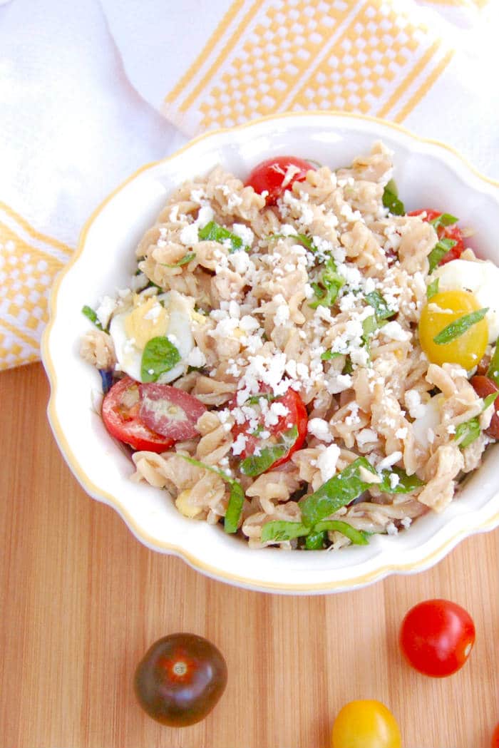 Canned tuna, cherry tomatoes, kalamata olives, hard-boiled eggs, and baby spinach are tossed with whole wheat pasta and a red wine vinaigrette in this quick and easy Nicoise Pasta Salad the whole family will love. Get the recipe via JessicaLevinson.com #NicoisePastaSalad #HealthyPastaSaladRecipe Nicoise Pasta Salad in Bowl
