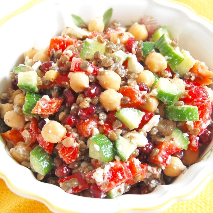 Lentil Chickpea Vegetable Salad with Feta | Protein and fiber-rich lentils and chickpeas, crunchy bell peppers and Persian cucumbers, sweet pomegranate seeds, and salty feta cheese are tossed together in a lemony maple-mustard vinaigrette for a kid-friendly and adult approved lunchbox salad. Get this gluten-free, nut-free, vegetarian, and vegan-friendly recipe via JessicaLevinson.com #LentilSaladRecipe #VegetarianLentilSalad Lentil Chickpea Vegetable Salad Recipe Close Up