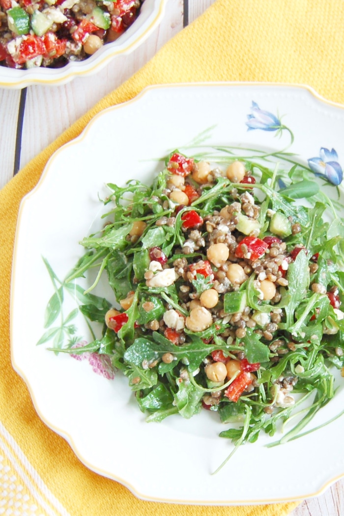 Lentil Chickpea Vegetable Salad with Feta | Protein and fiber-rich lentils and chickpeas, crunchy bell peppers and Persian cucumbers, sweet pomegranate seeds, and salty feta cheese are tossed together in a lemony maple-mustard vinaigrette for a kid-friendly and adult approved lunchbox salad. Get this gluten-free, nut-free, vegetarian, and vegan-friendly recipe via JessicaLevinson.com #LentilSaladRecipe #VegetarianLentilSalad Lentil Chickpea Vegetable Salad on Plate