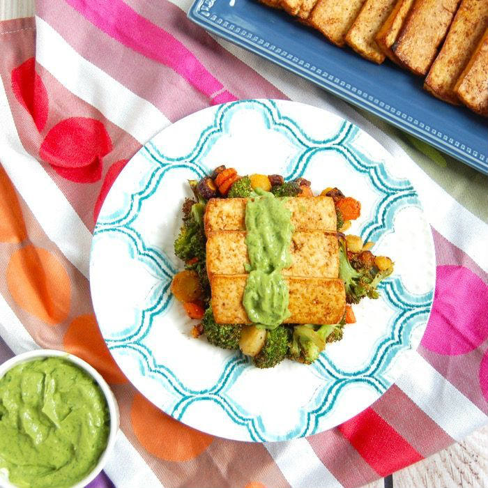 Grilled Tofu topped with with creamy Cilantro Avocado Sauce over a bed of roasted veggies